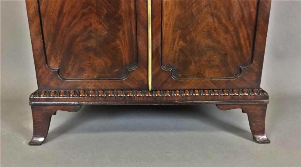 A Regency period mahogany secretaire cabinet featuring flame mahogany veneered doors with re-entrant corners, gadrooned borders, and bracket feet. View XIII