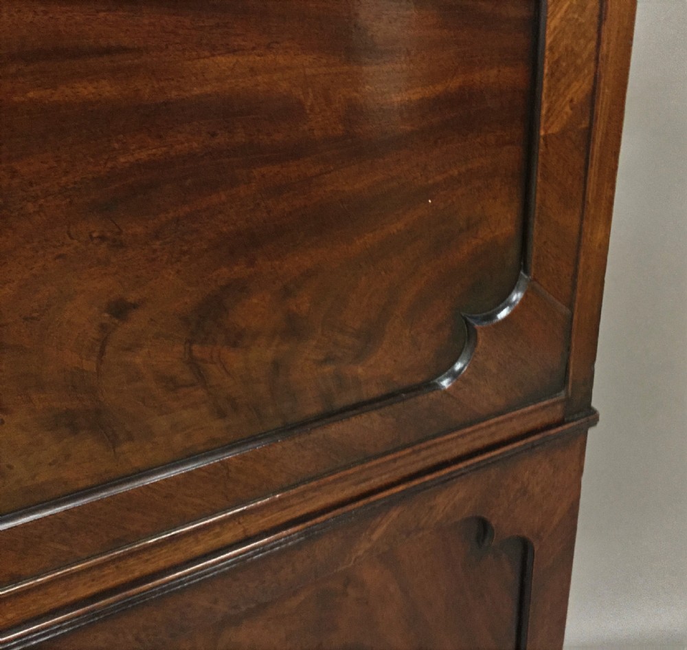 A Regency period mahogany secretaire cabinet featuring flame mahogany veneered doors with re-entrant corners, gadrooned borders, and bracket feet. View XV