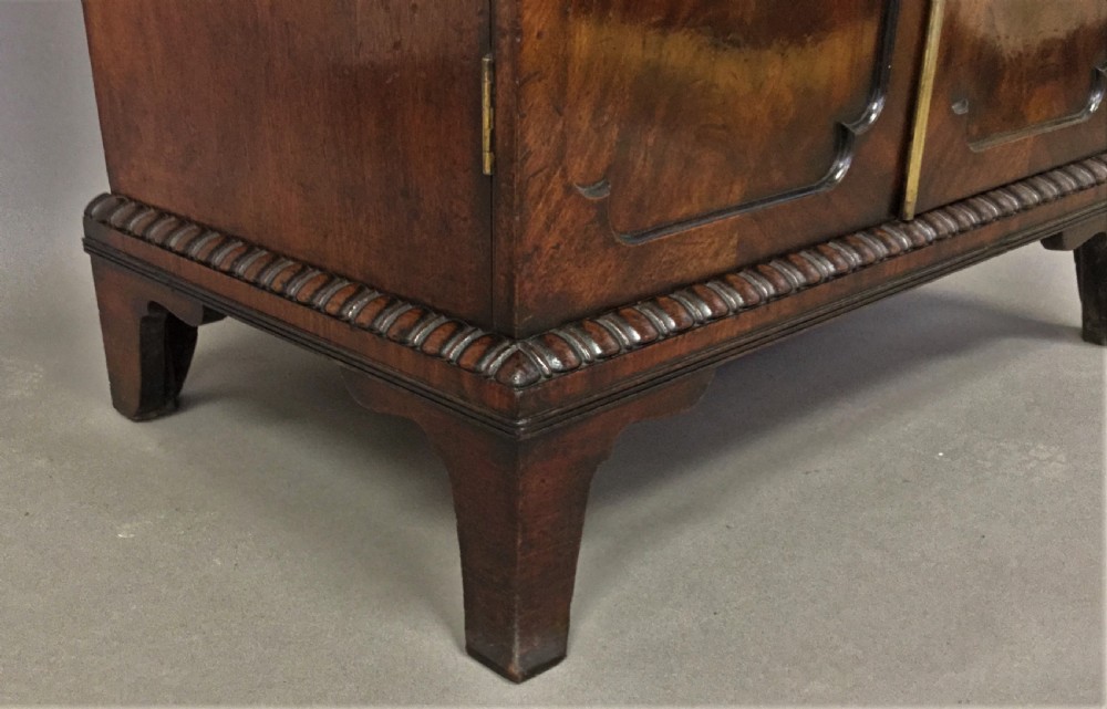 A Regency period mahogany secretaire cabinet featuring flame mahogany veneered doors with re-entrant corners, gadrooned borders, and bracket feet. View XXIII