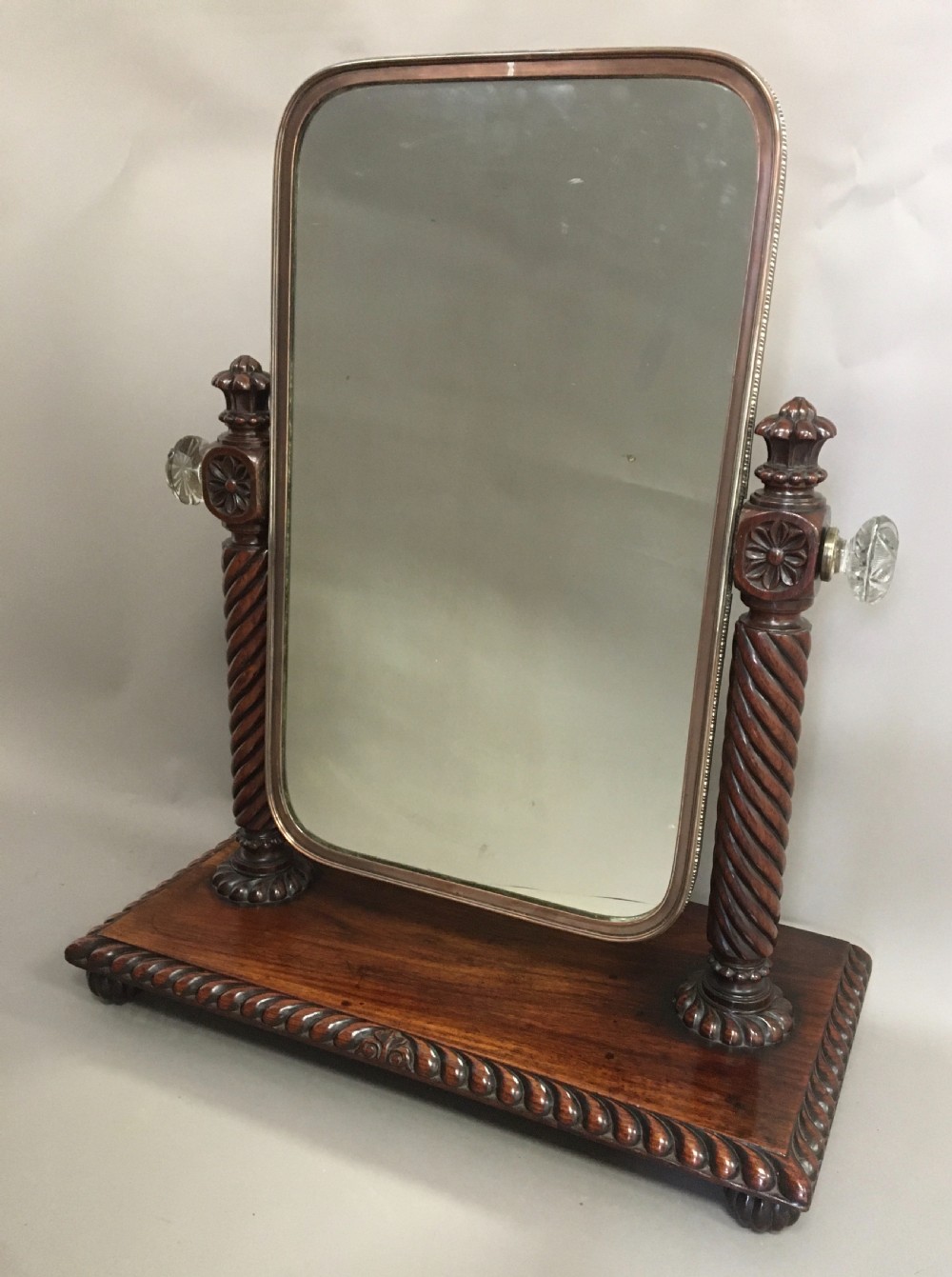 An antique Regency Anglo-Indian dark padouk timber dressing mirror featuring spiral twist columns, carved rope-twist base trim, glass side knobs, and a tall rectangular mirror plate. View II