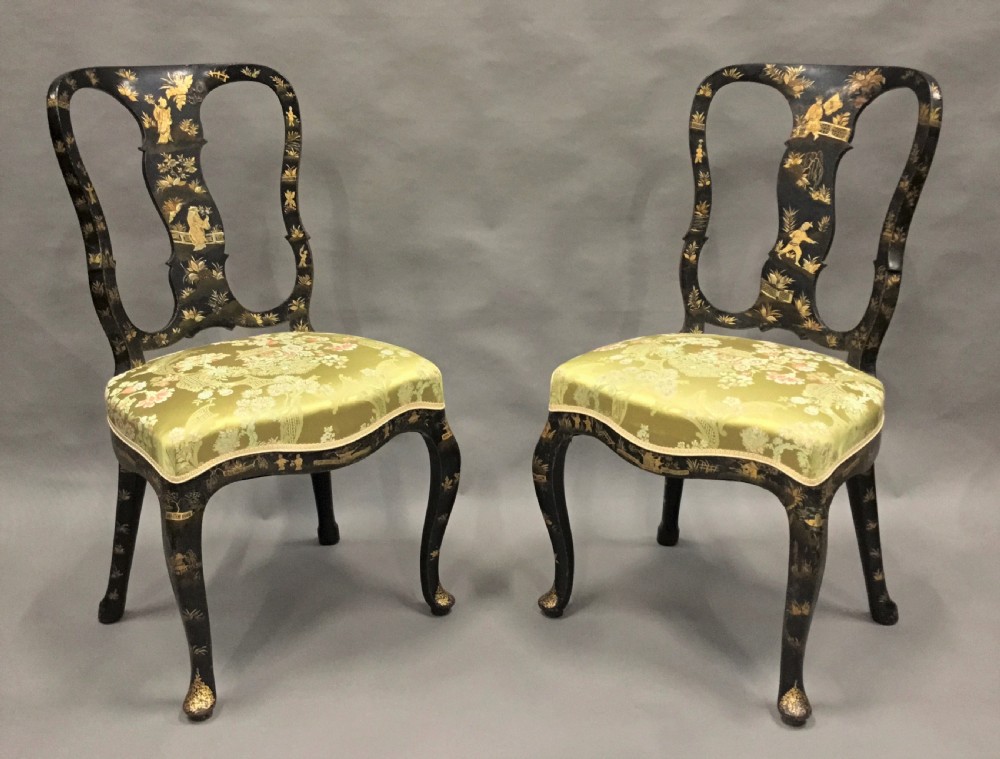 A pair of 18th-century Dutch black lacquered side chairs featuring gold chinoiserie motifs, shaped splat backs, cabriole legs, and green patterned silk seats.