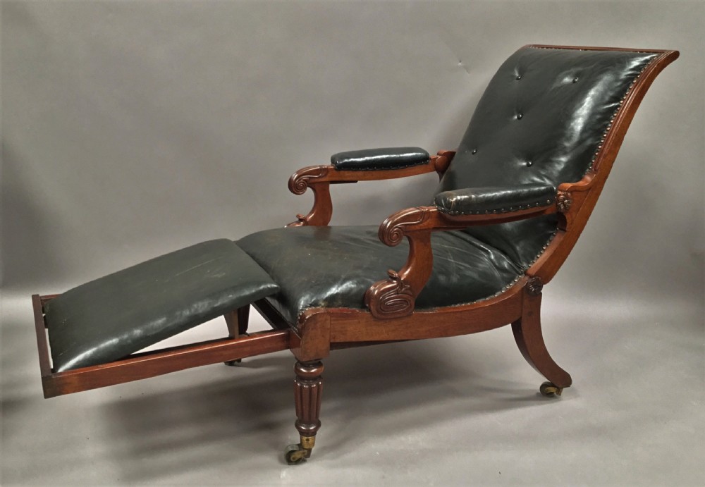 A Late Regency mahogany library armchair with dark green button-backed leather upholstery, carved scroll arms, and reeded front legs on brass castors. View III