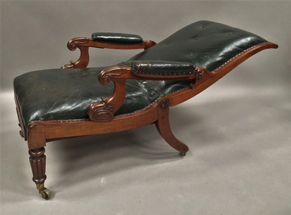 A Late Regency mahogany library armchair with dark green button-backed leather upholstery, carved scroll arms, and reeded front legs on brass castors. View VII