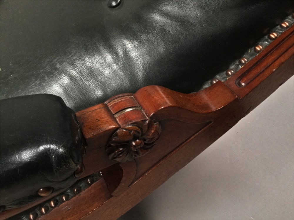 A Late Regency mahogany library armchair with dark green button-backed leather upholstery, carved scroll arms, and reeded front legs on brass castors. View XIV
