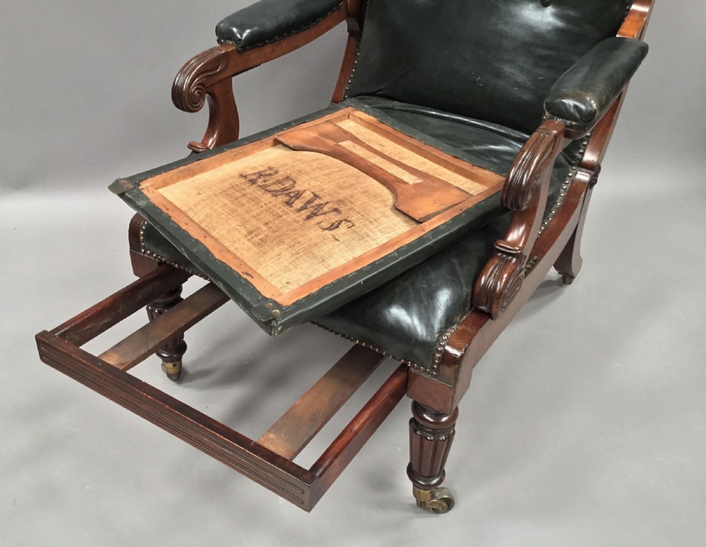 A Late Regency mahogany library armchair with dark green button-backed leather upholstery, carved scroll arms, and reeded front legs on brass castors. View XVIII