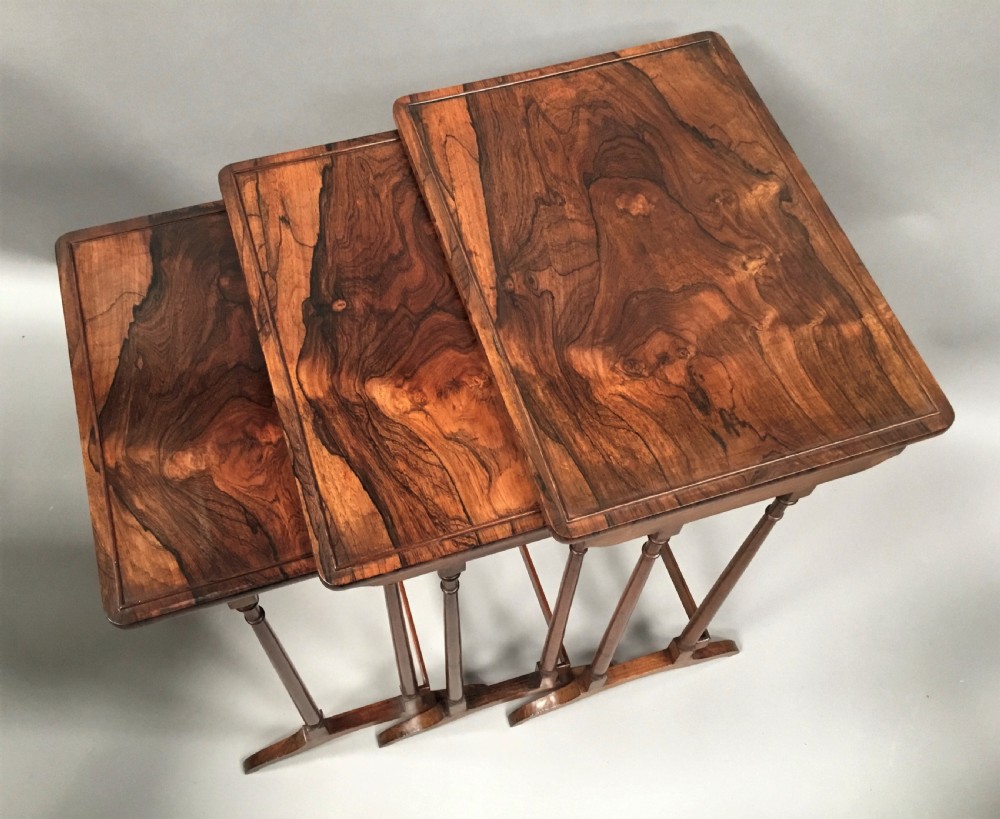 A set of three graduated Regency rosewood nesting tables featuring turned twin-spindle legs and trestle feet. View V