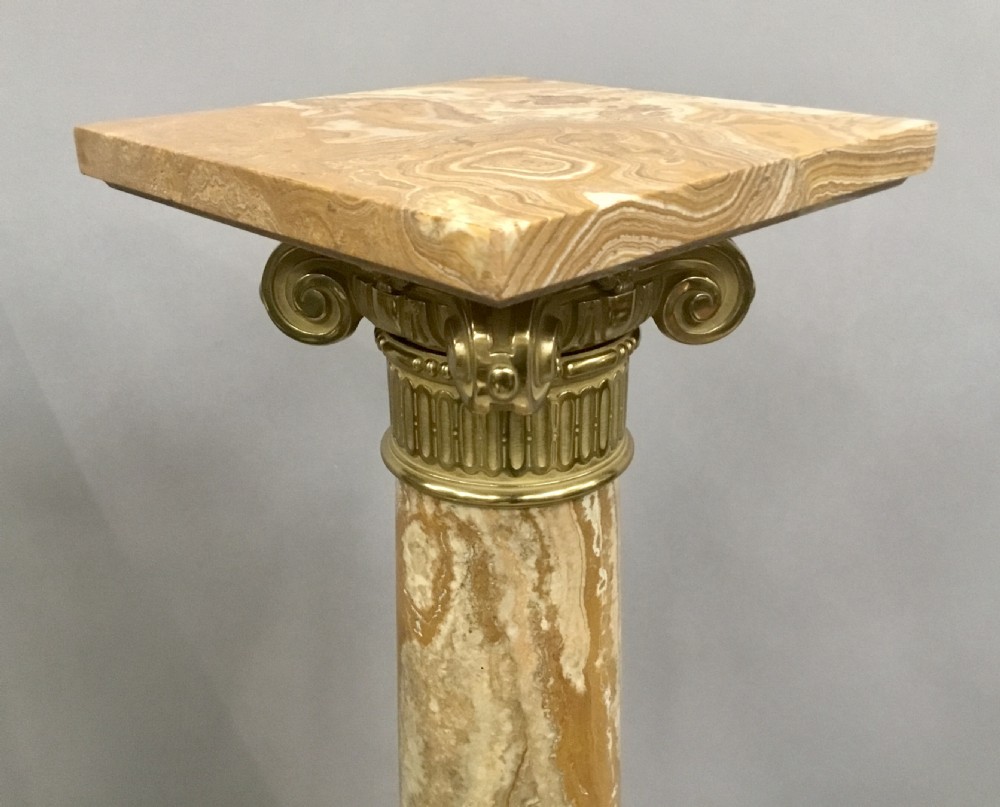 A pair of nineteenth-century Neoclassical pedestals featuring veined beige marble shafts, brass ormolu Ionic capitals, and square marble bases. View IV
