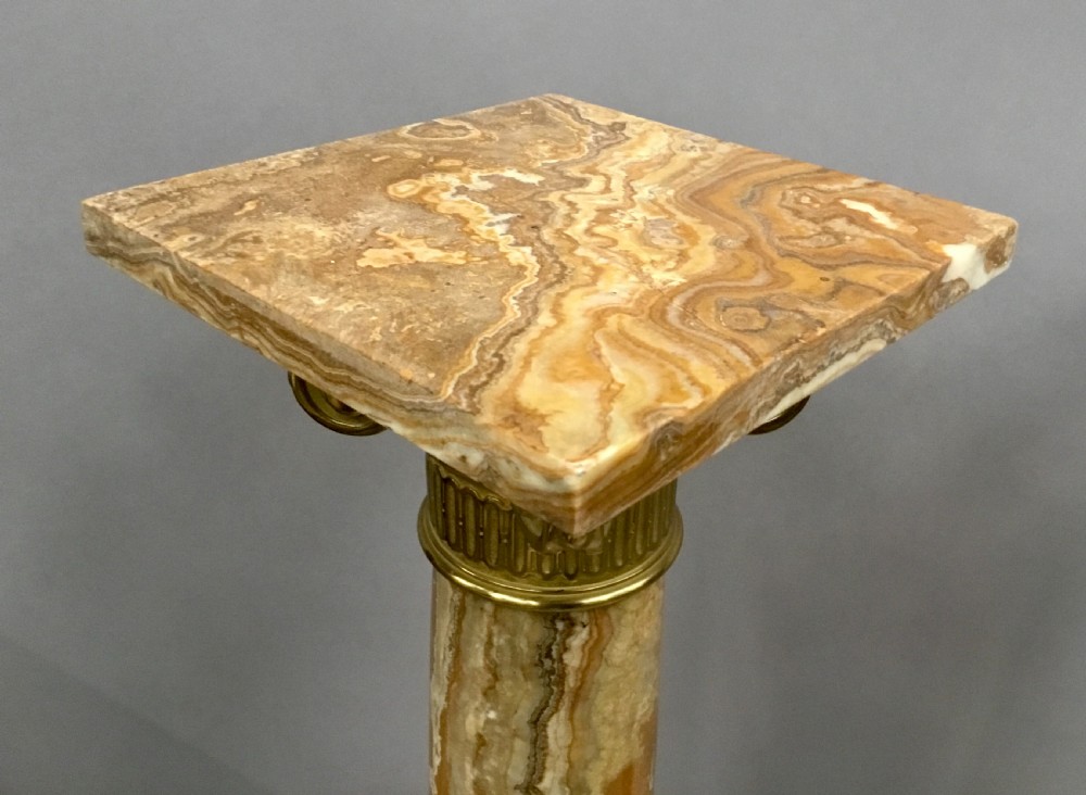 A pair of nineteenth-century Neoclassical pedestals featuring veined beige marble shafts, brass ormolu Ionic capitals, and square marble bases. View XXII