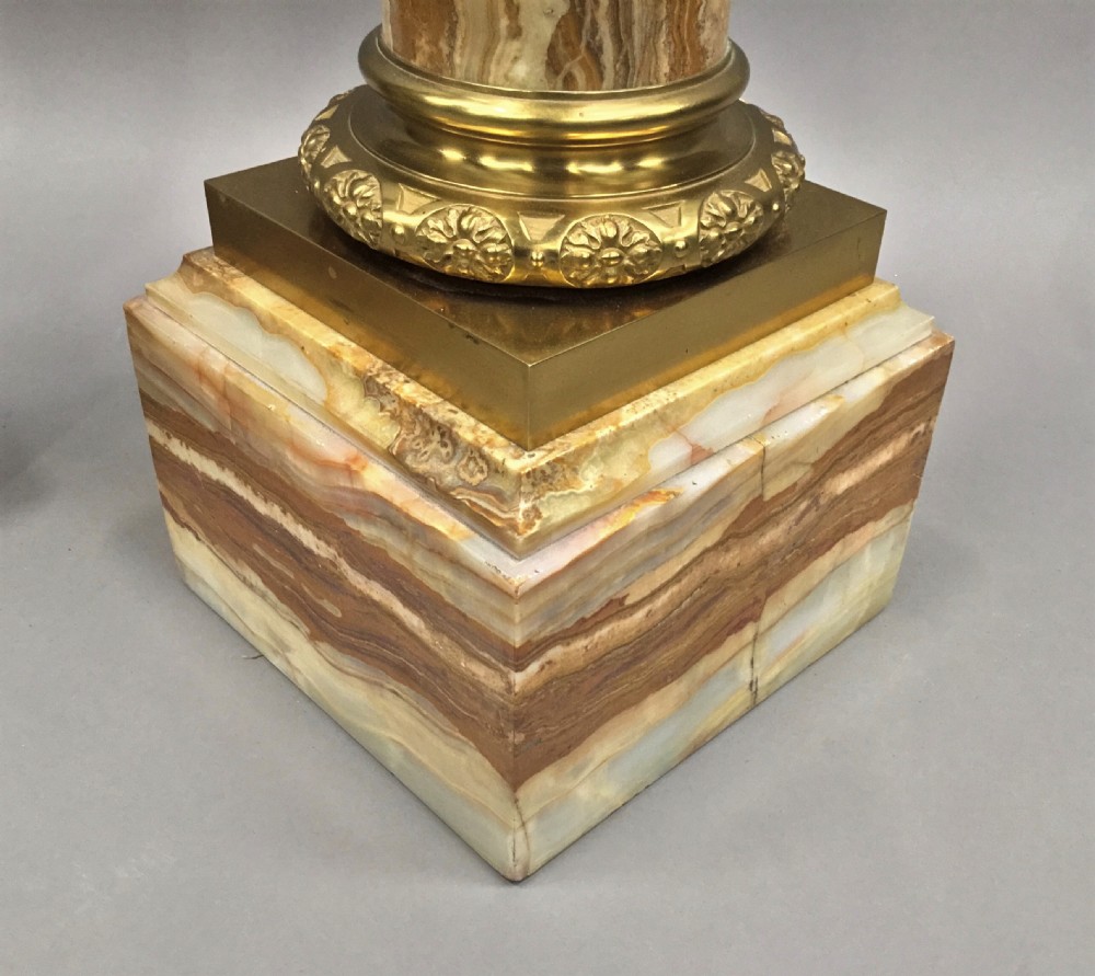 A pair of nineteenth-century Neoclassical pedestals featuring veined beige marble shafts, brass ormolu Ionic capitals, and square marble bases. View XXV
