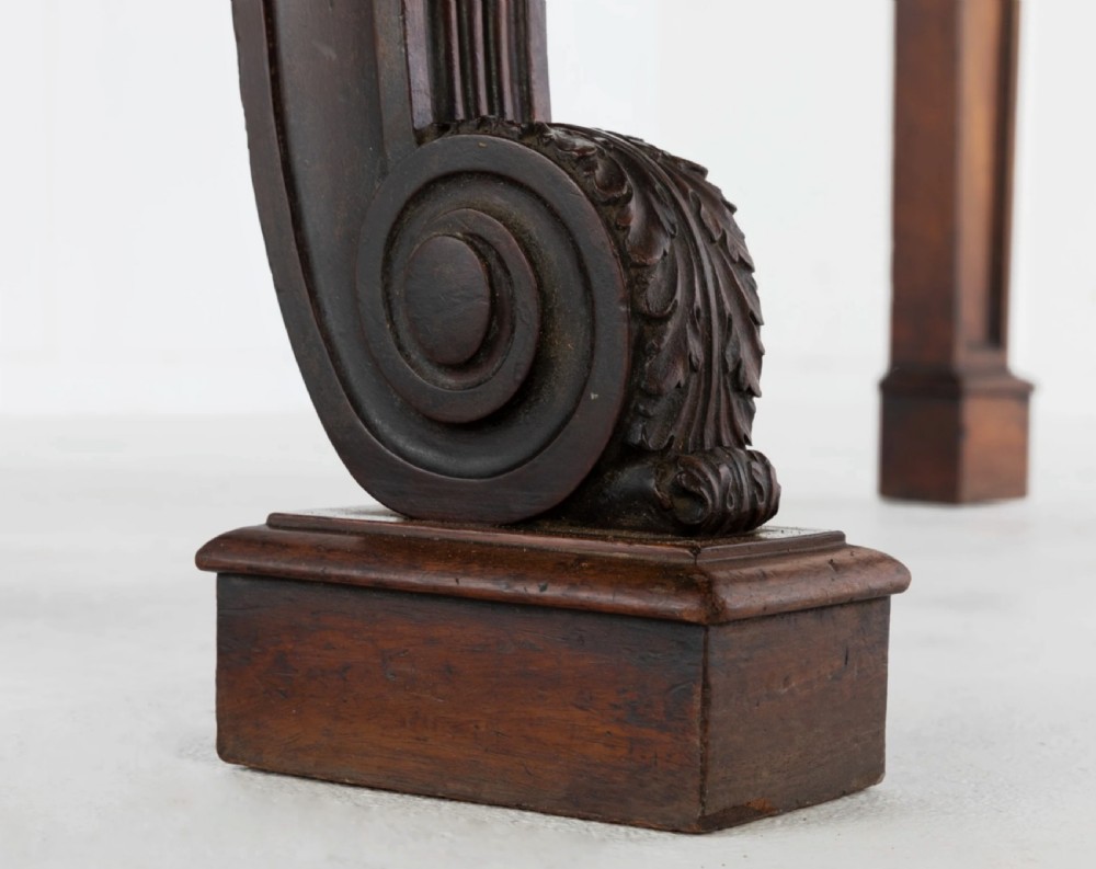A Late Regency mahogany console table featuring a raised gallery back, carved acanthus leaf scroll legs, and rosette corner blocks. View IX