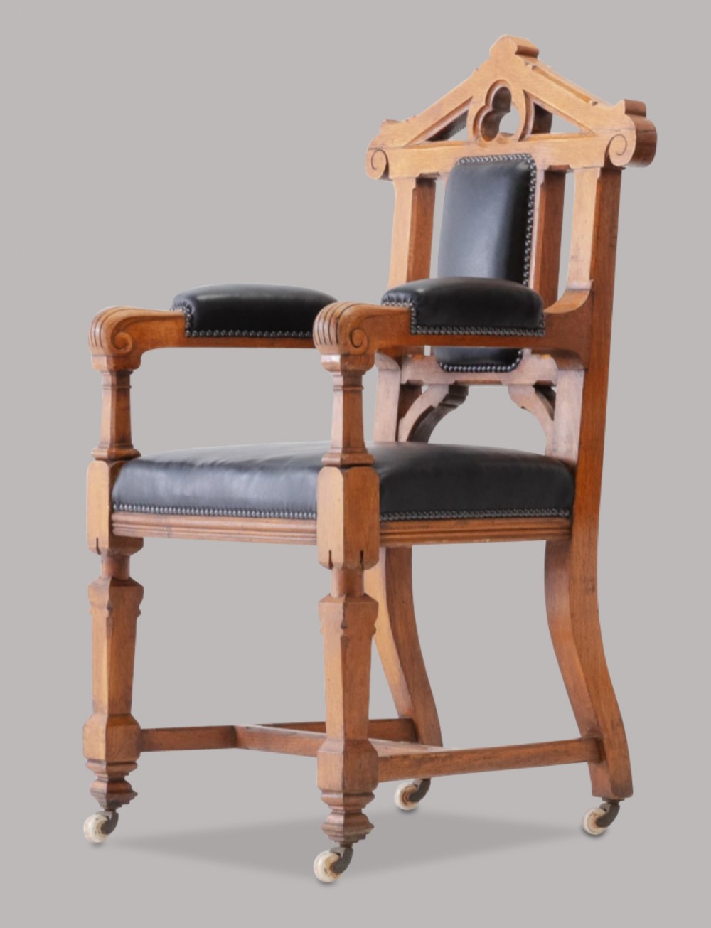 A pair of 19th-century Gothic Revival golden oak open armchairs with black leather upholstery and carved trefoil pediments. View III