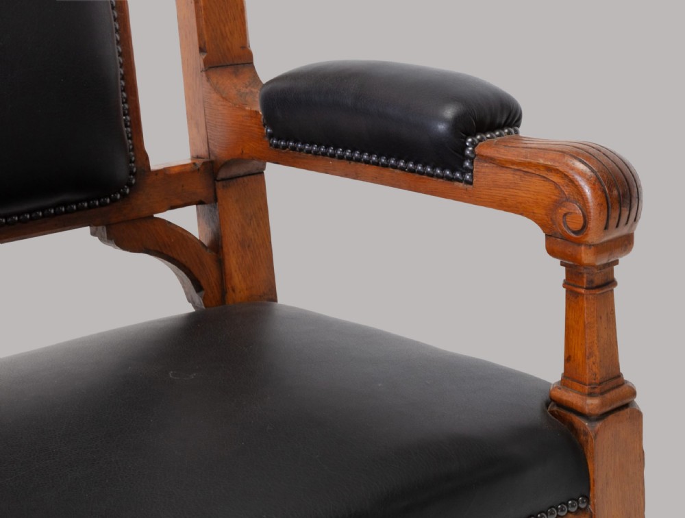 A pair of 19th-century Gothic Revival golden oak open armchairs with black leather upholstery and carved trefoil pediments. View IV