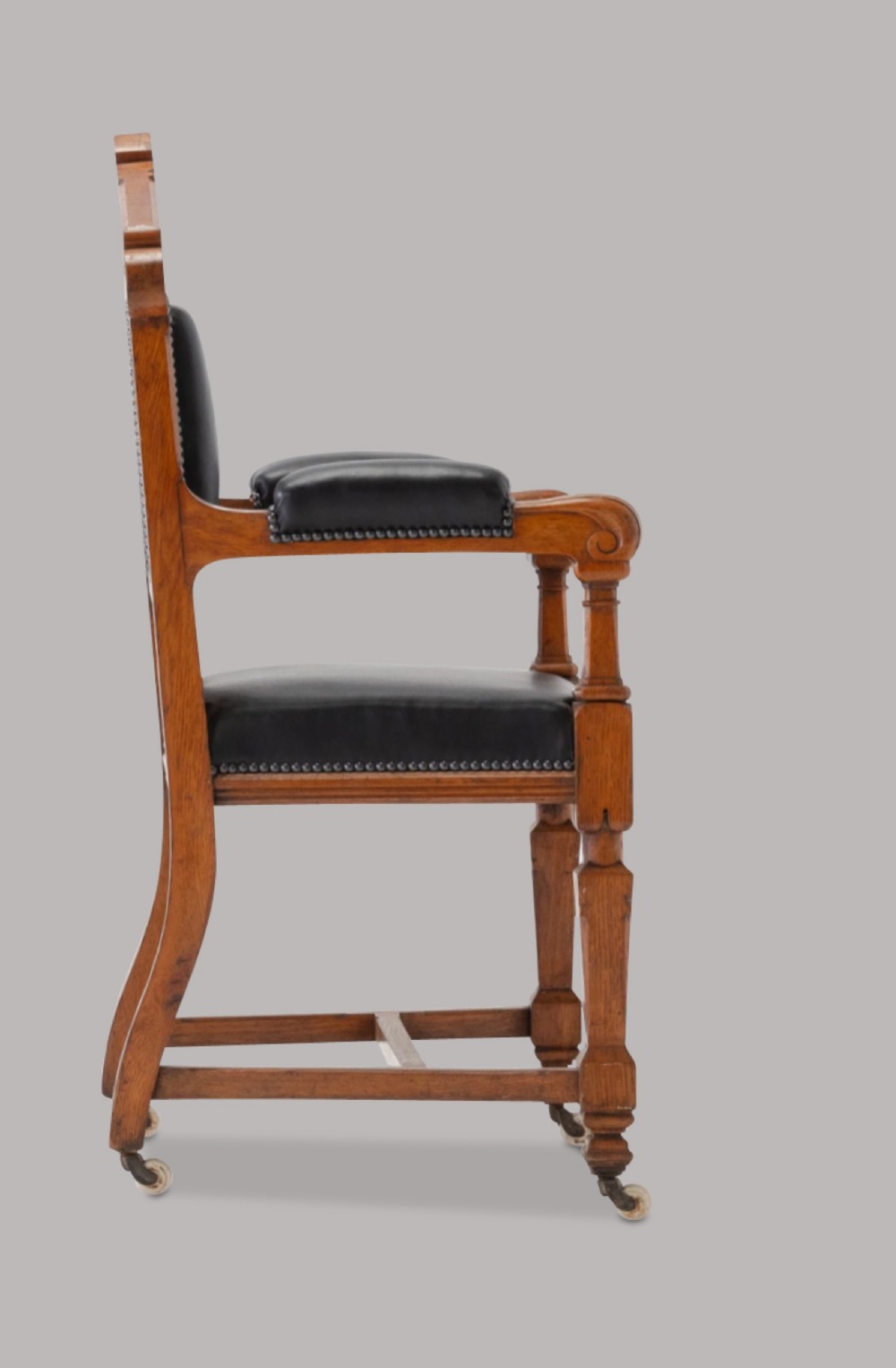 A pair of 19th-century Gothic Revival golden oak open armchairs with black leather upholstery and carved trefoil pediments. View VII