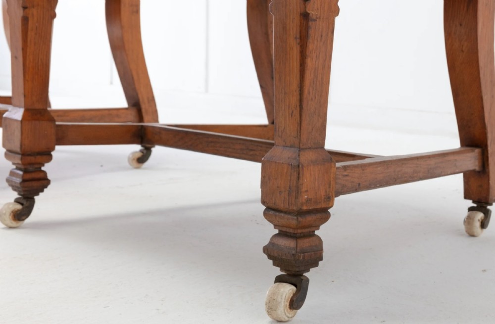 A pair of 19th-century Gothic Revival golden oak open armchairs with black leather upholstery and carved trefoil pediments. View XI