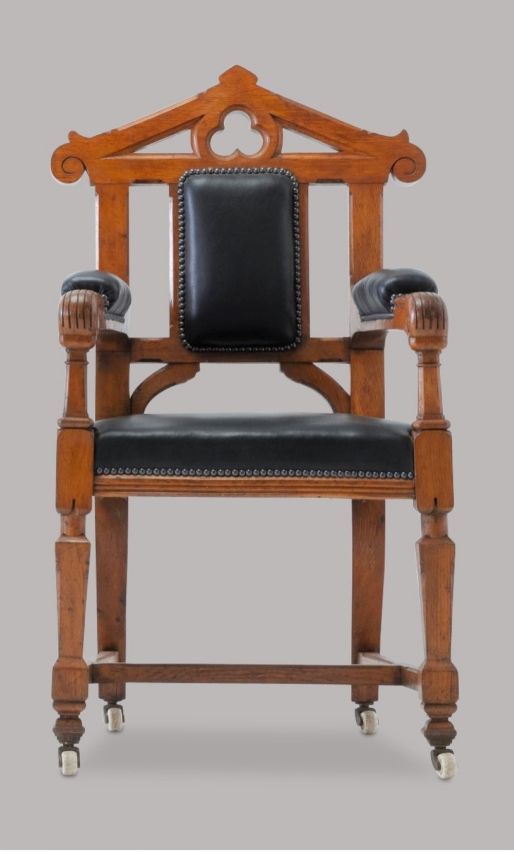 A pair of 19th-century Gothic Revival golden oak open armchairs with black leather upholstery and carved trefoil pediments. View XIII