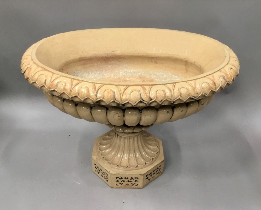 A cream glazed terracotta pedestal urn with a gadrooned lower bowl and an octagonal base featuring incised markings. View XVI