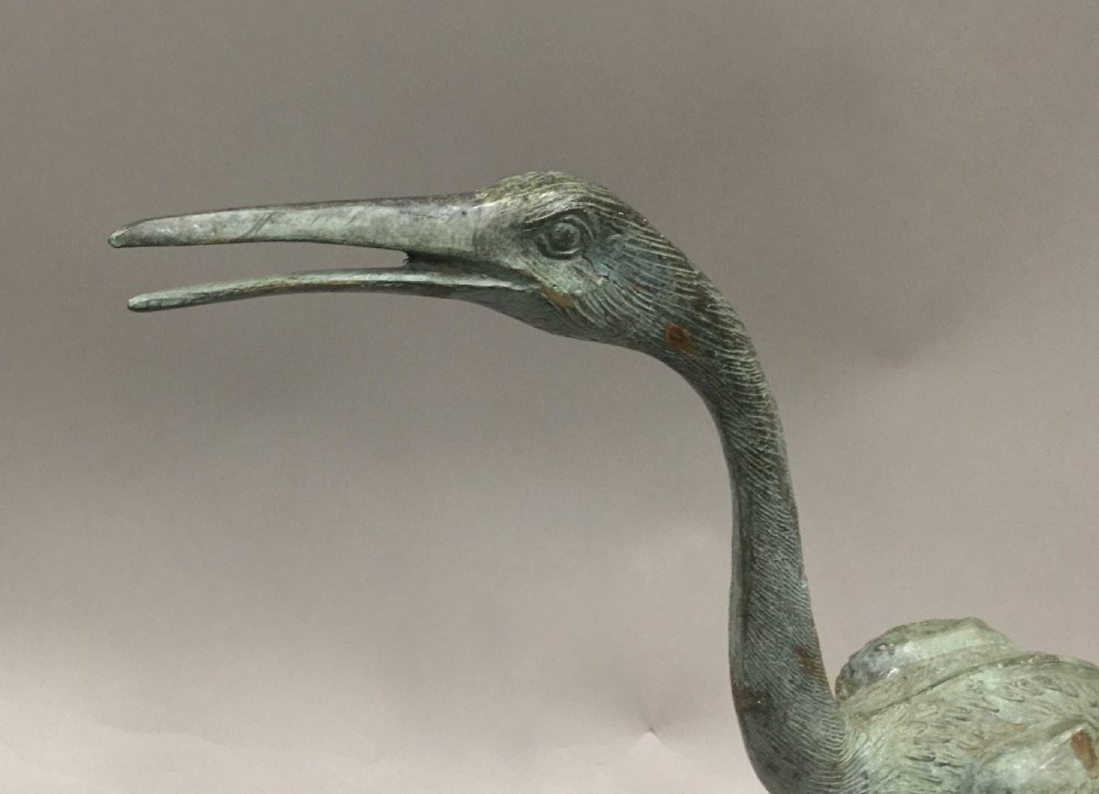 An early 20th-century cast bronze sculpture of a crane with an open beak and weathered verdigris green patina, standing on a textured base. View III