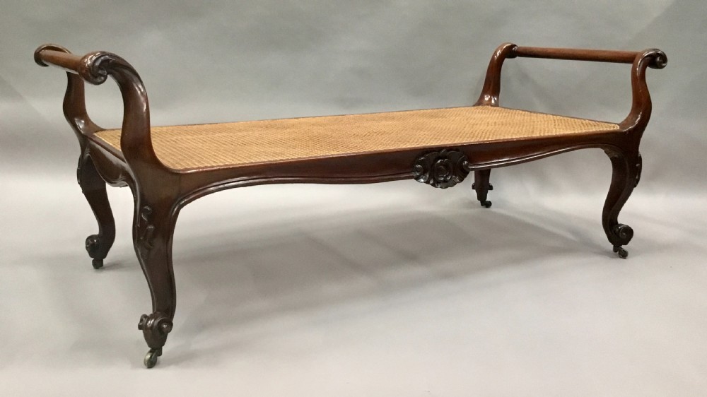 A mid-19th century mahogany window seat featuring a hand-woven cane panel, scrolled side handles, and carved cabriole legs with brass castors. View III