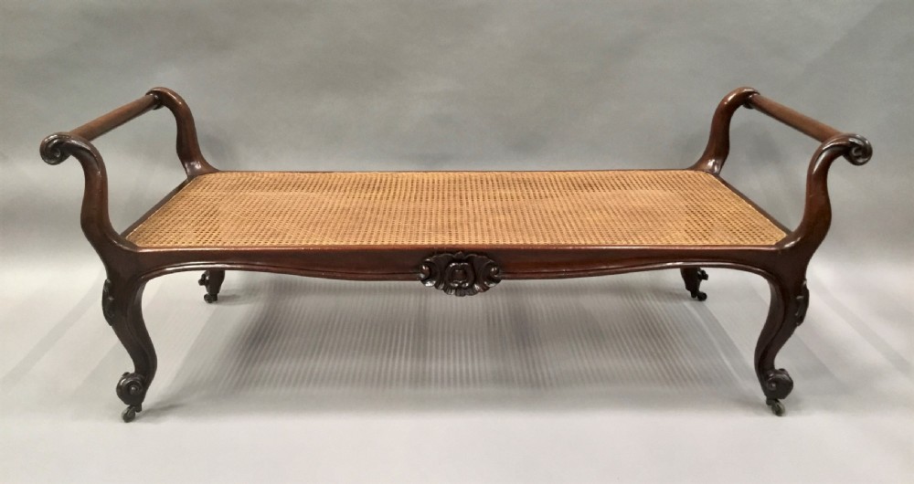 A mid-19th century mahogany window seat featuring a hand-woven cane panel, scrolled side handles, and carved cabriole legs with brass castors. View VII