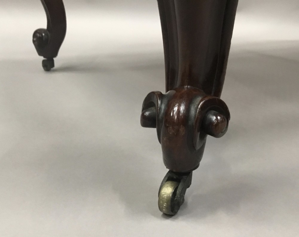 A mid-19th century mahogany window seat featuring a hand-woven cane panel, scrolled side handles, and carved cabriole legs with brass castors. View XV