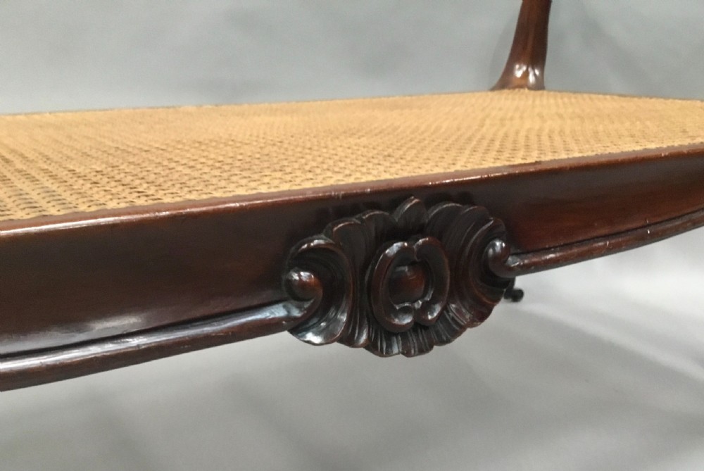 A mid-19th century mahogany window seat featuring a hand-woven cane panel, scrolled side handles, and carved cabriole legs with brass castors. View XVI