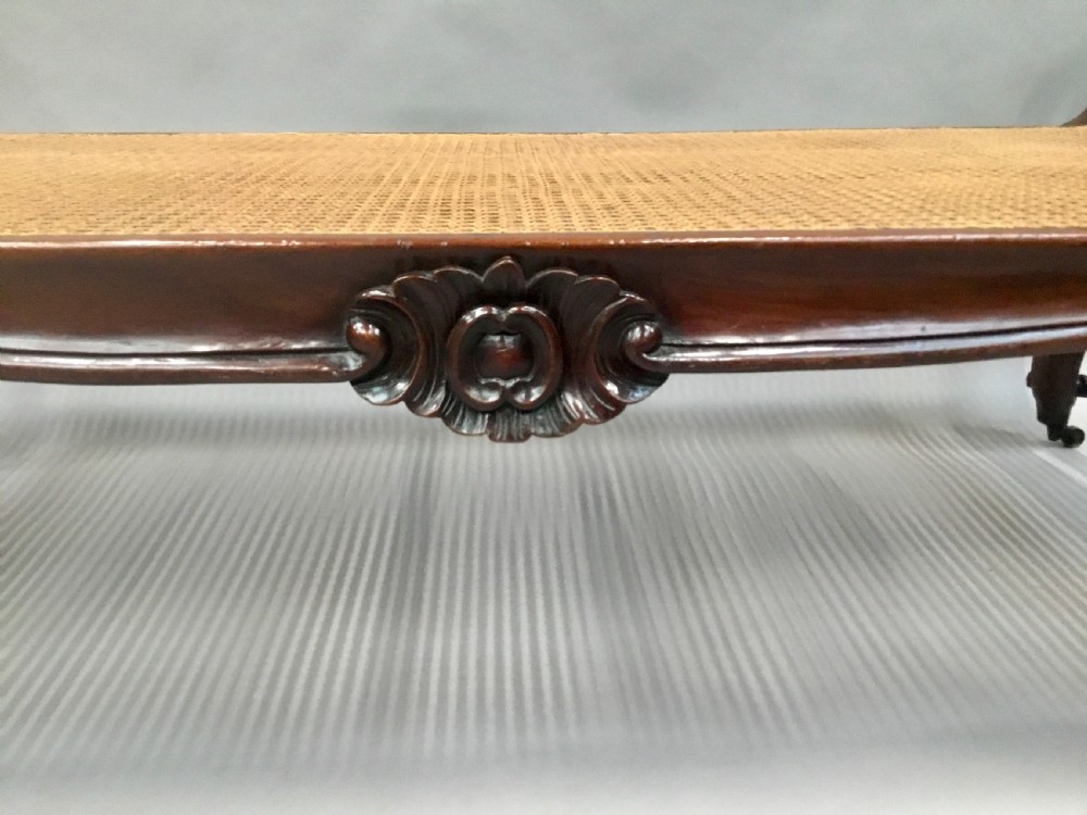A mid-19th century mahogany window seat featuring a hand-woven cane panel, scrolled side handles, and carved cabriole legs with brass castors. View XVIII