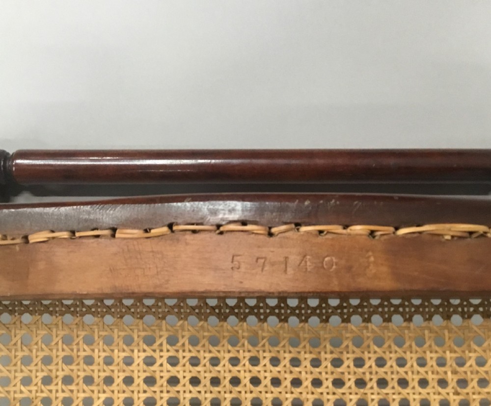 A mid-19th century mahogany window seat featuring a hand-woven cane panel, scrolled side handles, and carved cabriole legs with brass castors. View XIX