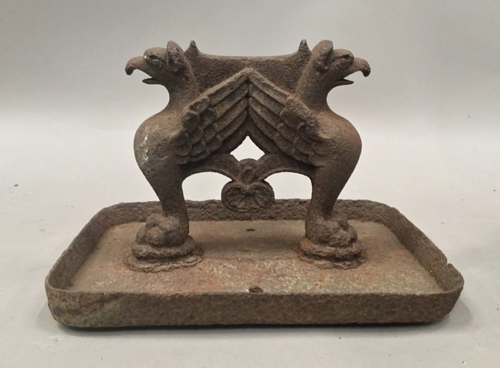 A pair of antique cast iron boot scrapers featuring sculpted griffin side supports and rectangular drip trays with an oxidised surface. View IV