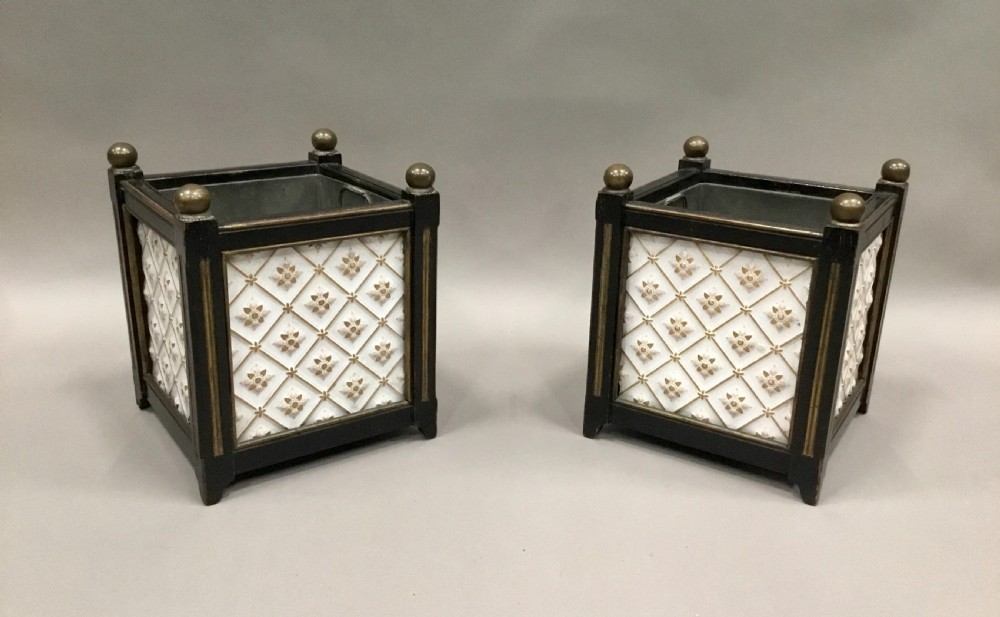 A pair of 19th-century square ebonised wood jardinieres featuring cream ceramic Minton tiles with raised star motifs, brass ball finials, and internal metal liners.