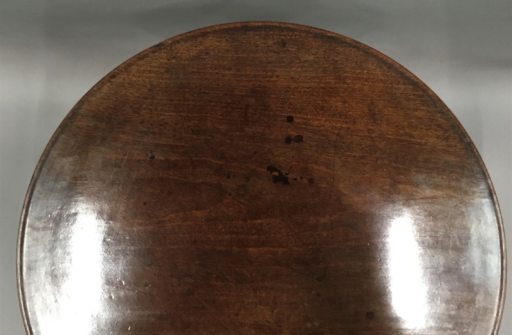 A Georgian dark mahogany tilt-top table featuring a circular top tilted vertically on a turned stem with three cabriole legs. View VIII