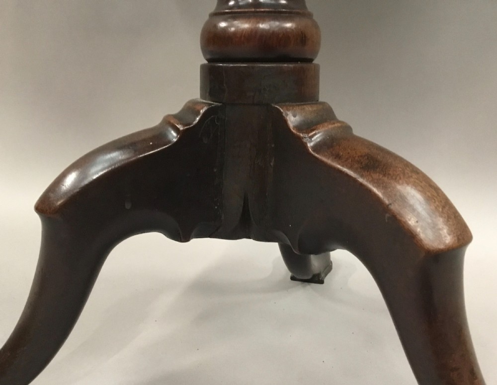 A Georgian dark mahogany tilt-top table featuring a circular top tilted vertically on a turned stem with three cabriole legs. View X