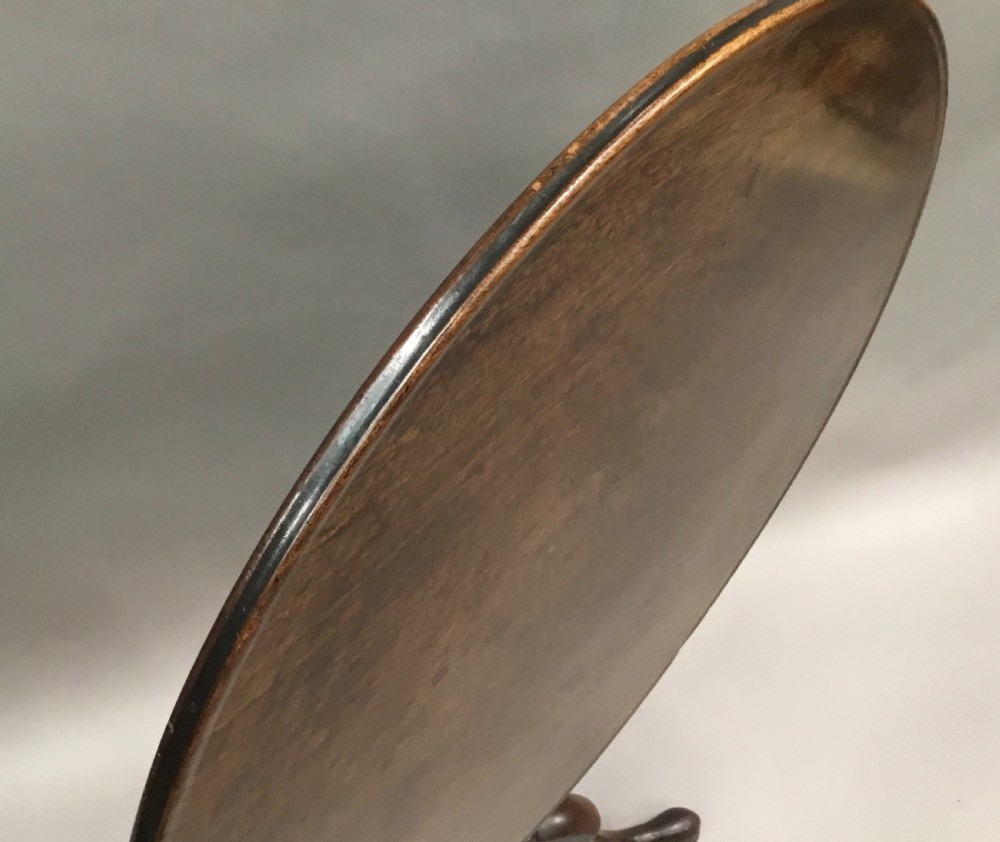 A Georgian dark mahogany tilt-top table featuring a circular top tilted vertically on a turned stem with three cabriole legs. View XI
