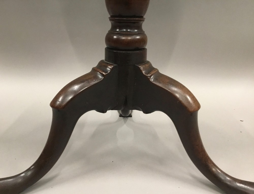 A Georgian dark mahogany tilt-top table featuring a circular top tilted vertically on a turned stem with three cabriole legs. View XVI