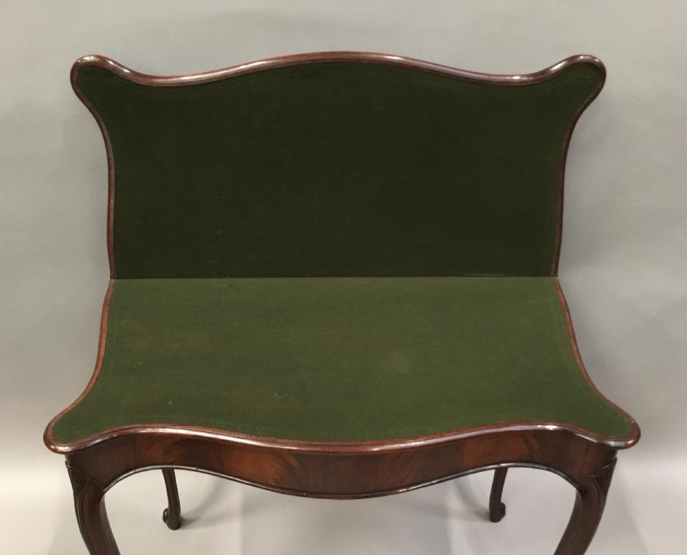 A George III mahogany Hepplewhite card table featuring a serpentine apron, shaped cabriole legs, and a hinged fold-over top. View IV