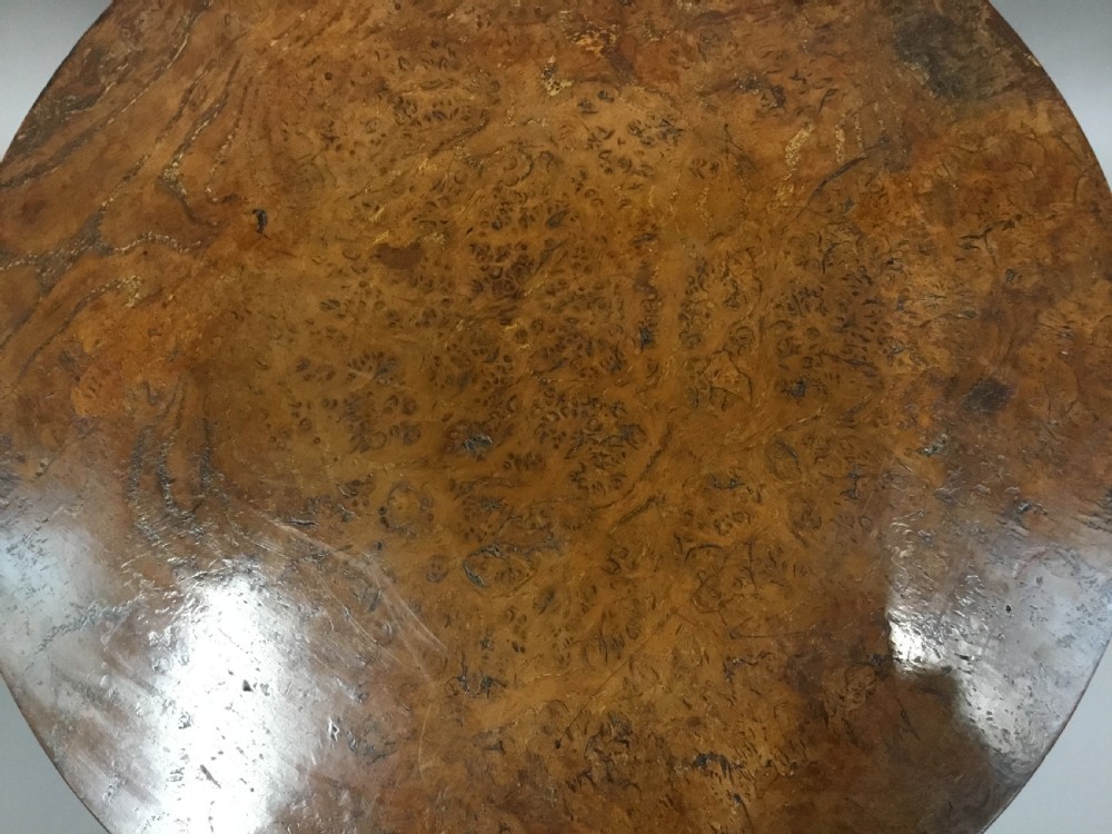 A Regency burr elm occasional table featuring a circular top with detailed grain, supported by an octagonal column and a triform base on bun feet. View X