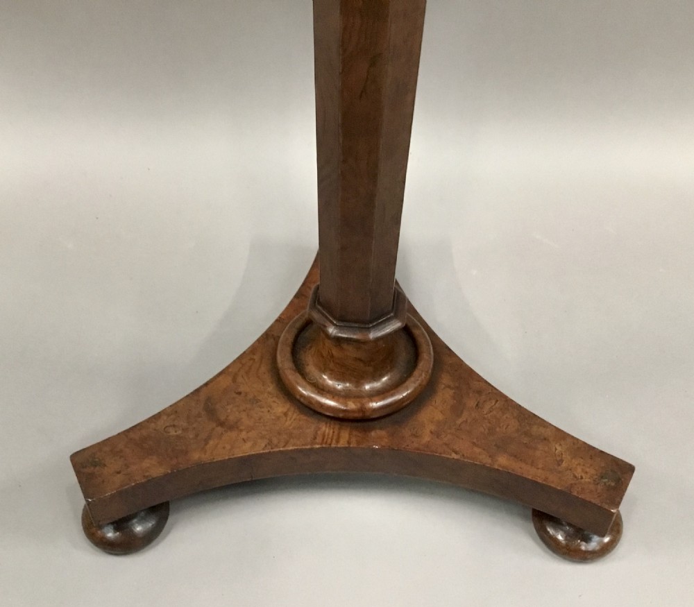A Regency burr elm occasional table featuring a circular top with detailed grain, supported by an octagonal column and a triform base on bun feet. View XII