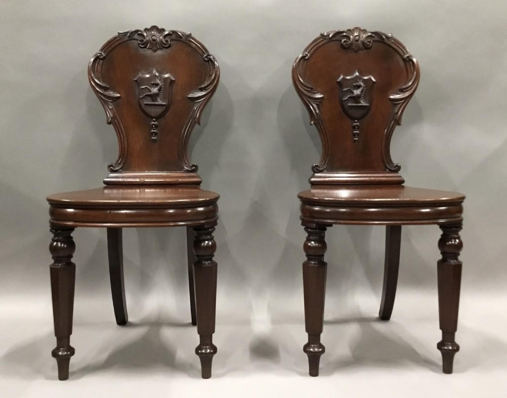 A pair of dark George IV mahogany hall chairs featuring carved backrest scrolls, crests depicting a hippocampus, and turned front legs. View III