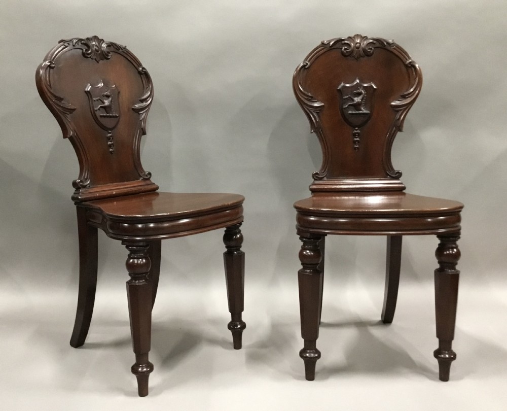 A pair of dark George IV mahogany hall chairs featuring carved backrest scrolls, crests depicting a hippocampus, and turned front legs. View VI