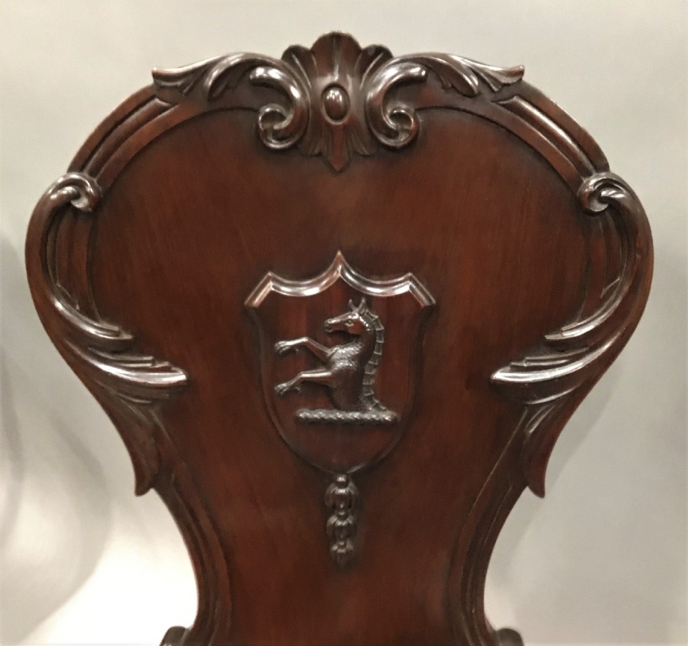 A pair of dark George IV mahogany hall chairs featuring carved backrest scrolls, crests depicting a hippocampus, and turned front legs. View XI