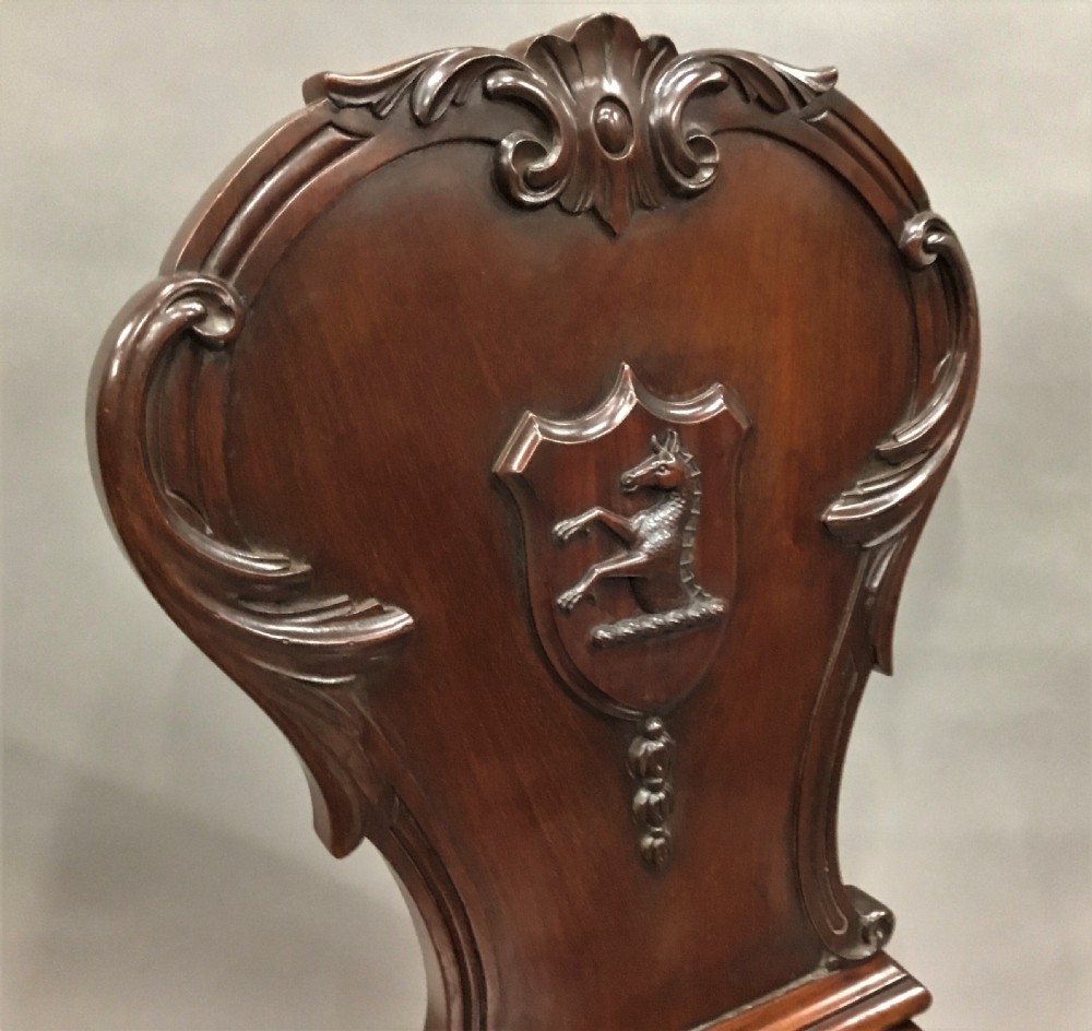 A pair of dark George IV mahogany hall chairs featuring carved backrest scrolls, crests depicting a hippocampus, and turned front legs. View XIV