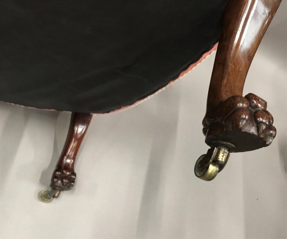 A Regency mahogany armchair upholstered in pink fabric, featuring carved lion-head arm terminals and hairy paw feet on brass castors. View VIII