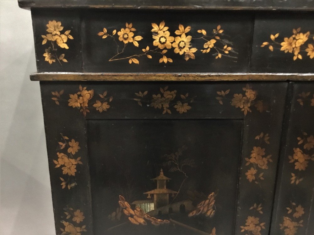 A black lacquered Regency chiffonier side cabinet featuring gold gilded Chinoiserie landscapes, floral borders, a top gallery shelf, and two cupboard doors. View XV