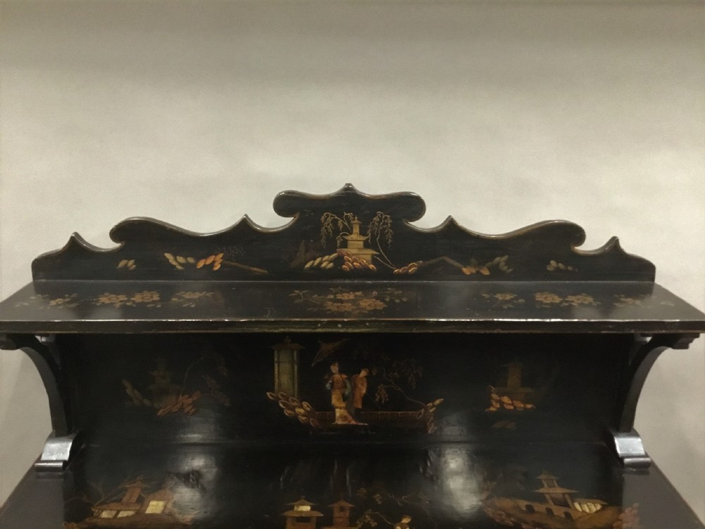 A black lacquered Regency chiffonier side cabinet featuring gold gilded Chinoiserie landscapes, floral borders, a top gallery shelf, and two cupboard doors. View XVII