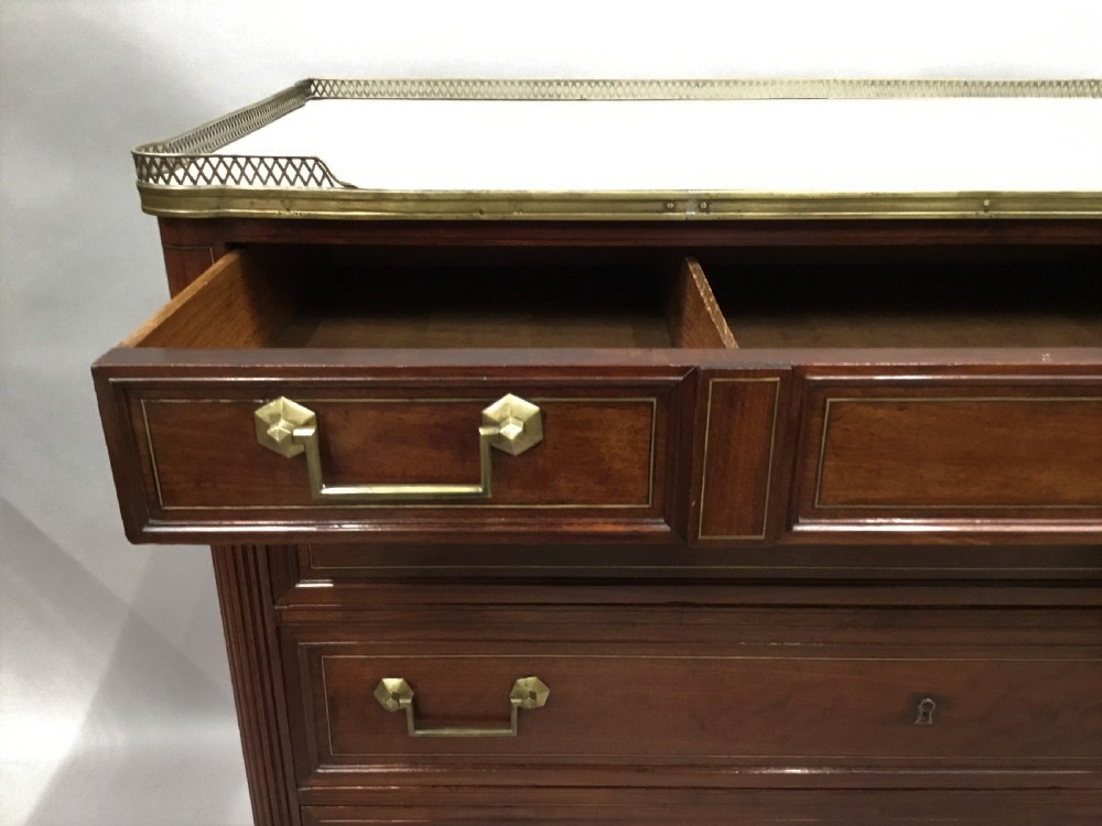 A late 18th-century French Louis XVI neoclassical commode in figured mahogany with a top brass gallery, four drawers, fluted corner stiles, angular brass handles, and turned tapered legs. View VII