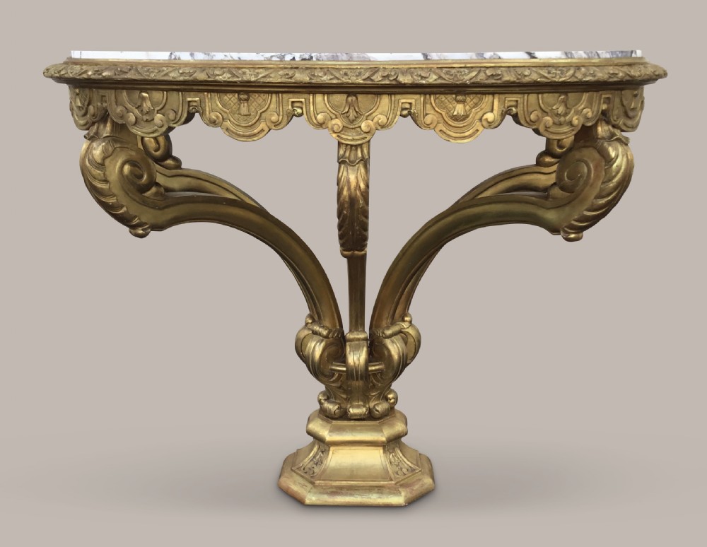 A 19th-century giltwood console table in the Kentian manner featuring a variegated white and grey marble top, carved apron, and central pedestal support with scrolled legs. View II