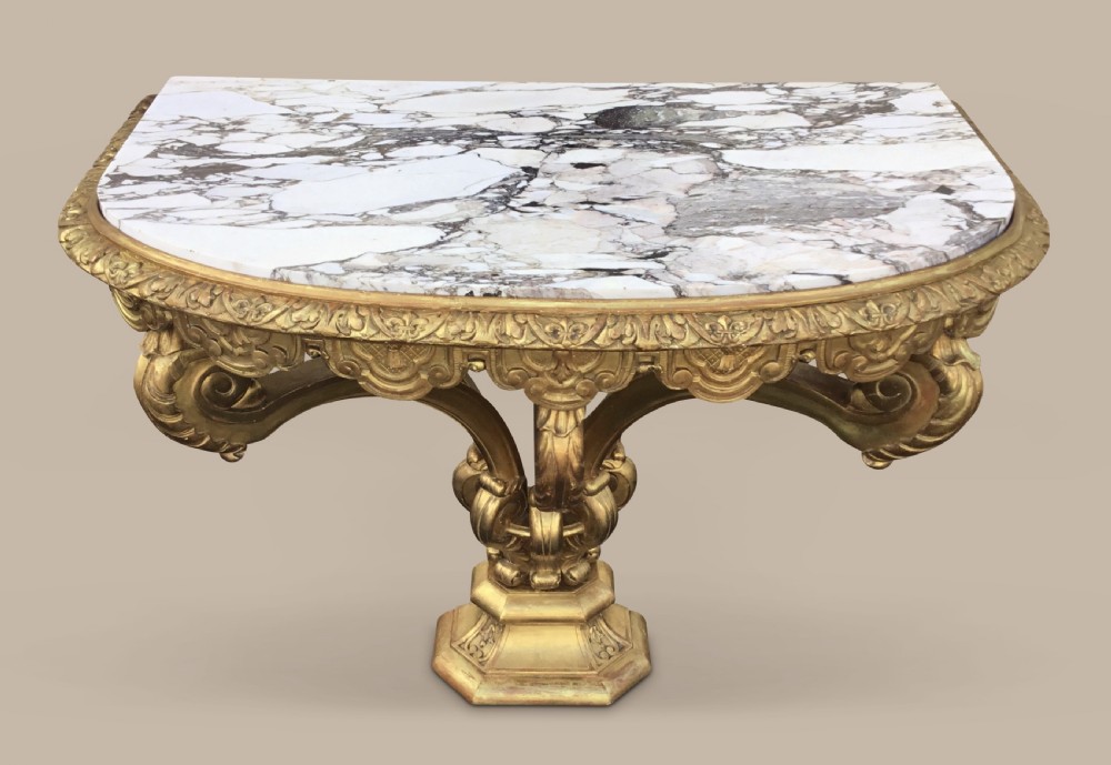 A 19th-century giltwood console table in the Kentian manner featuring a variegated white and grey marble top, carved apron, and central pedestal support with scrolled legs. View III
