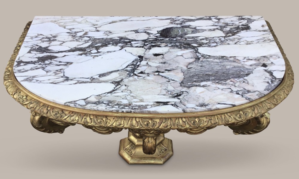 A 19th-century giltwood console table in the Kentian manner featuring a variegated white and grey marble top, carved apron, and central pedestal support with scrolled legs. View VIII