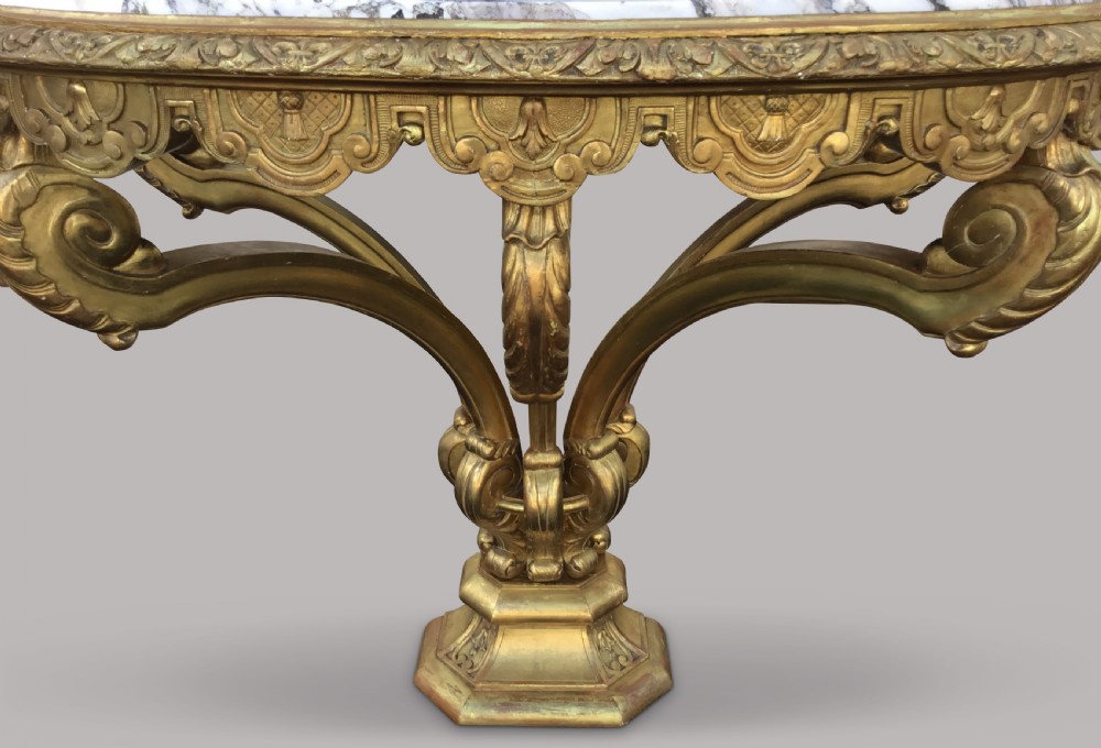 A 19th-century giltwood console table in the Kentian manner featuring a variegated white and grey marble top, carved apron, and central pedestal support with scrolled legs. View IX