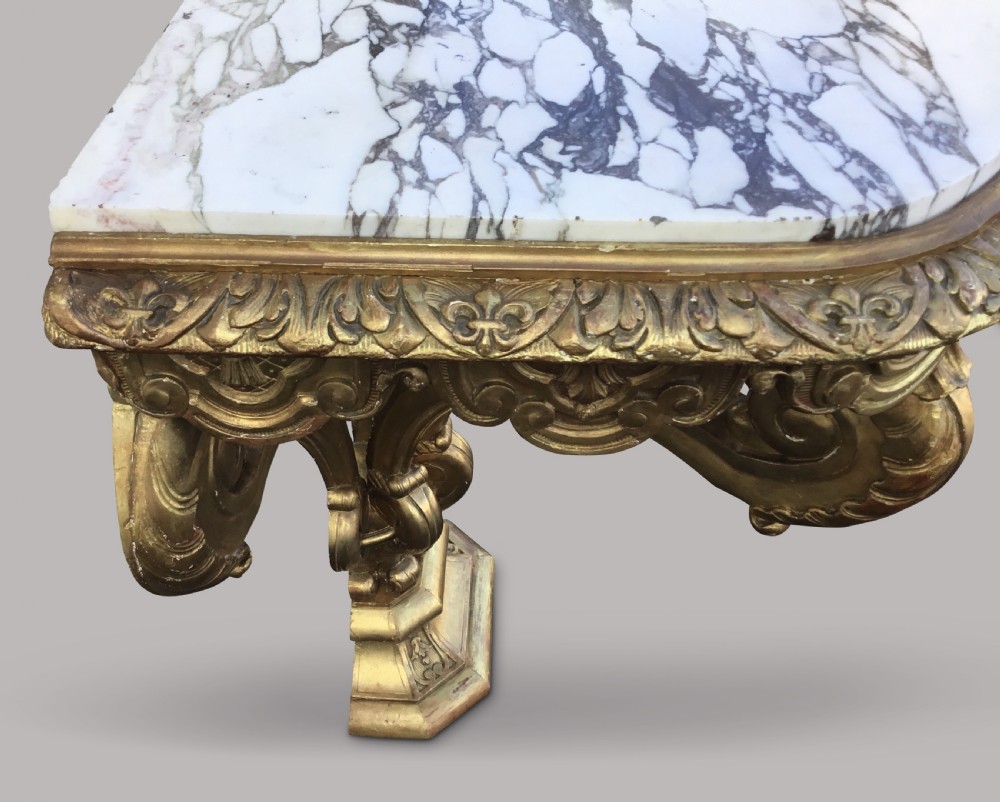 A 19th-century giltwood console table in the Kentian manner featuring a variegated white and grey marble top, carved apron, and central pedestal support with scrolled legs. View XVIII