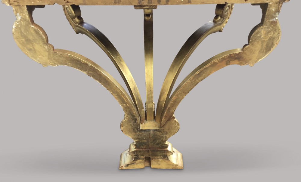 A 19th-century giltwood console table in the Kentian manner featuring a variegated white and grey marble top, carved apron, and central pedestal support with scrolled legs. View XXI